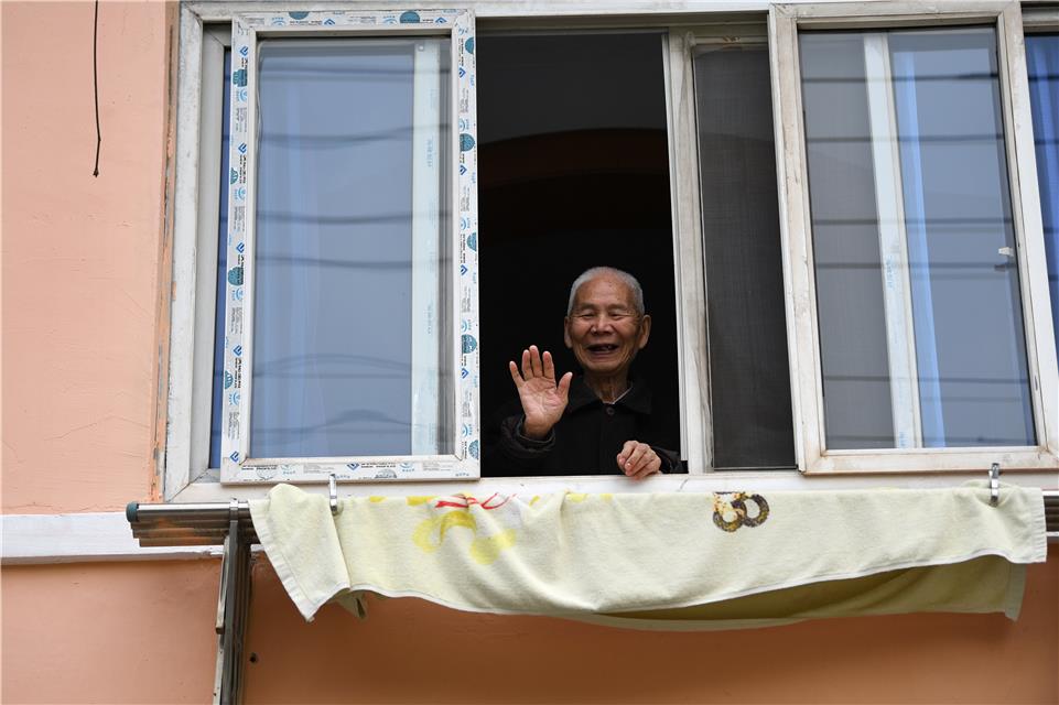 3月23日，武汉市青山区青山镇街船厂社区，一位爹爹在自家窗口和网格员打招呼。