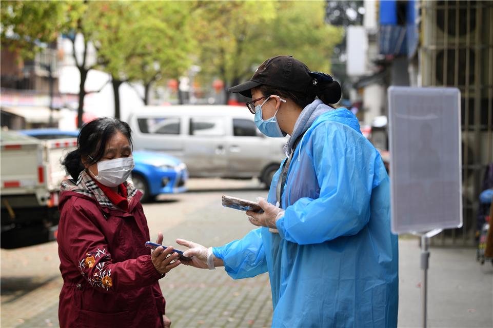 3月23日，武汉市青山区青山镇街船厂社区中百超市，店员在指导老年居民使用健康码。