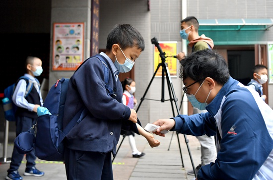 陕西省西安市各小学一至三年级开学复课。图为陕西省西安市新城区后宰门小学的学生进校时测量体温。新华社供图