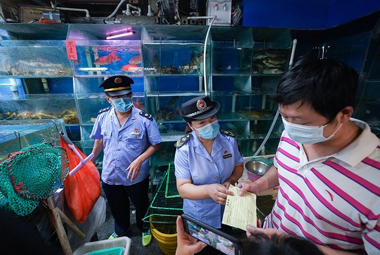 在海鲜水产大厅一家摊位前，市场监管局工作人员检查商户的进货票据。